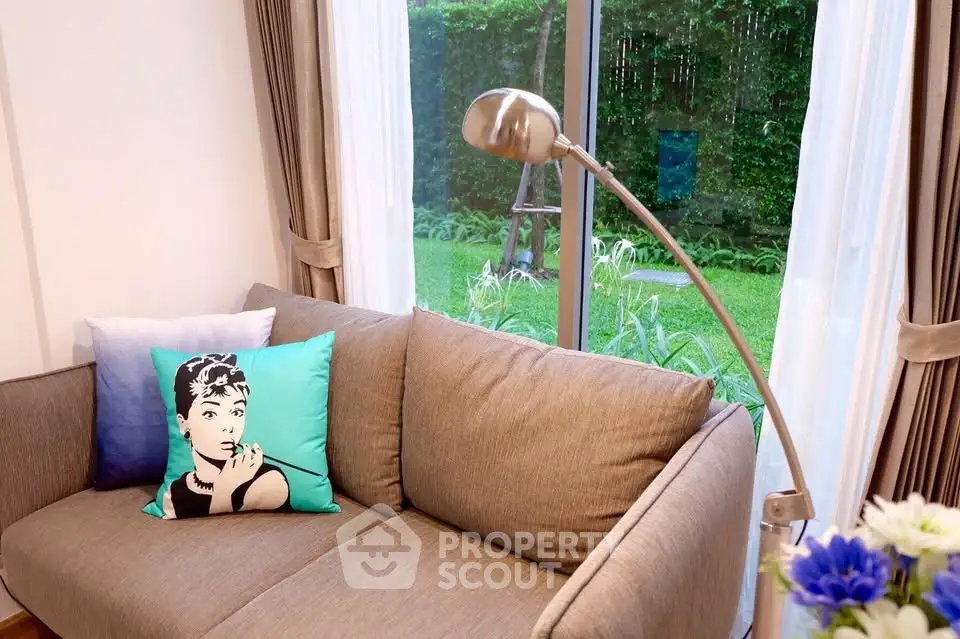 Cozy living room with stylish decor and garden view through large window.