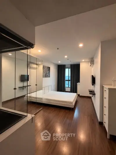 Spacious modern bedroom with wooden flooring and large window view