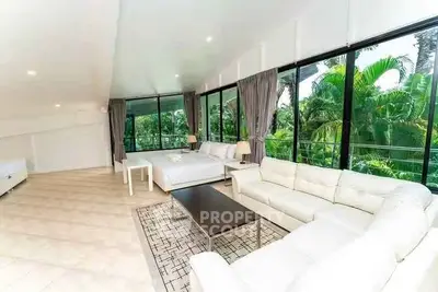 Spacious living room with large windows and lush garden view, featuring modern white furniture.