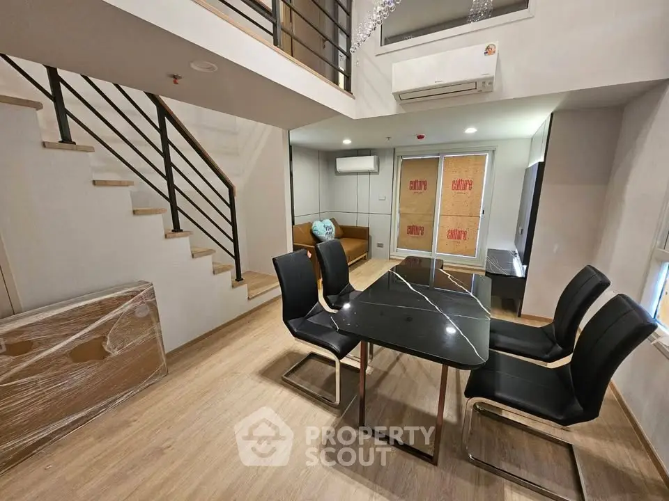 Modern duplex living room with sleek black dining table and stylish staircase
