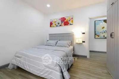Modern bedroom with stylish decor and cozy ambiance, featuring elegant artwork and sleek furnishings.