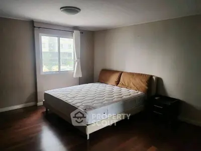 Spacious bedroom with large window and wooden flooring