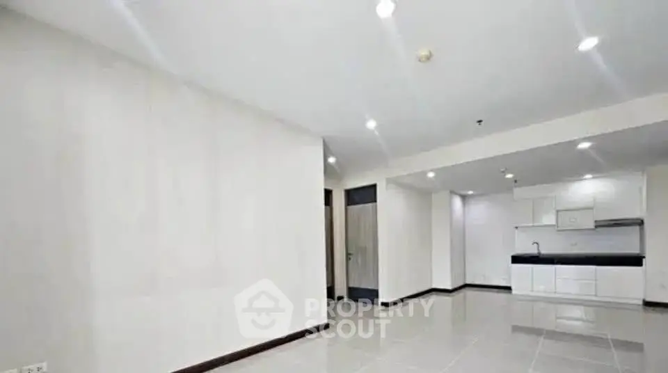 Spacious open-plan living area with modern kitchen in a bright apartment.