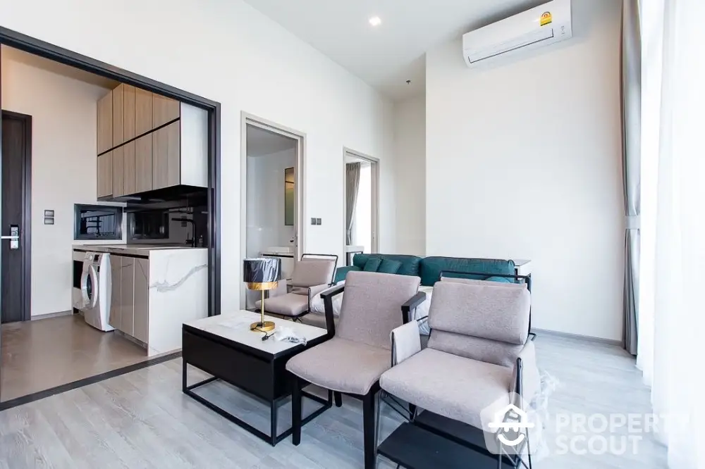 Modern living room with sleek furniture and open kitchen layout in a bright apartment.