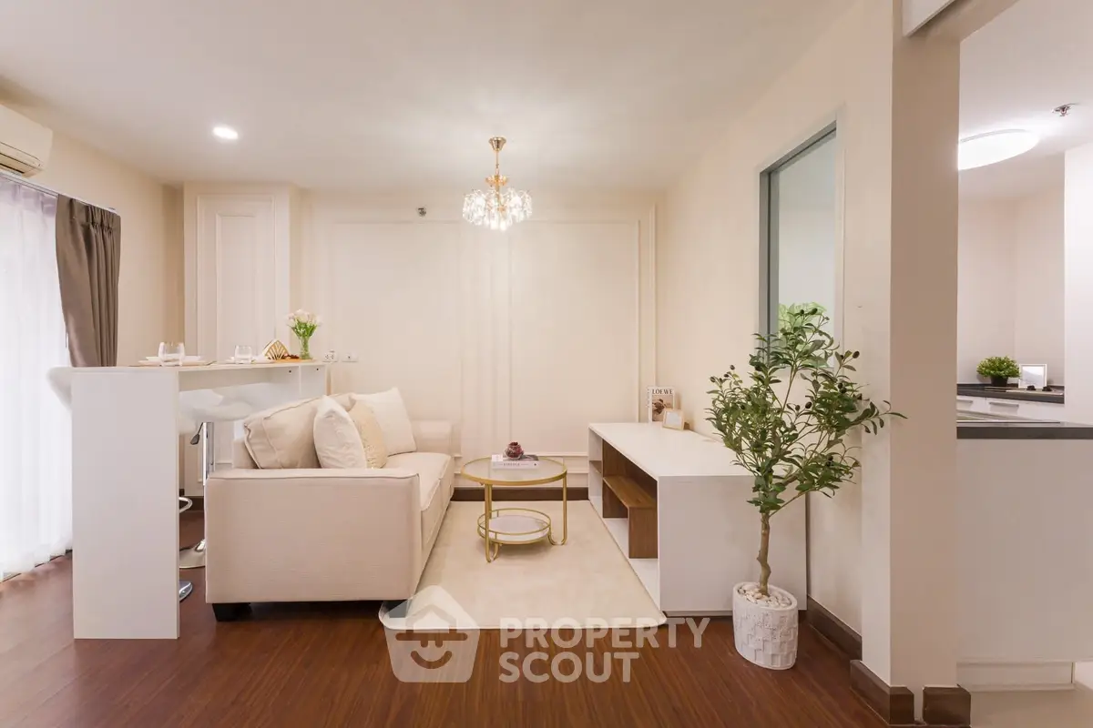 Elegant living room with modern decor and open layout, featuring a cozy sofa and stylish chandelier.