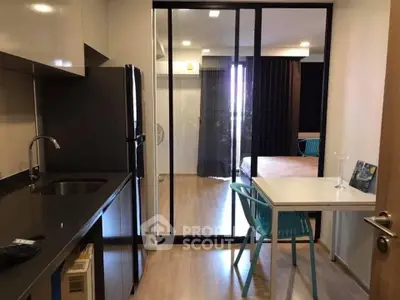 Modern kitchen with sleek black appliances and open layout leading to dining area.