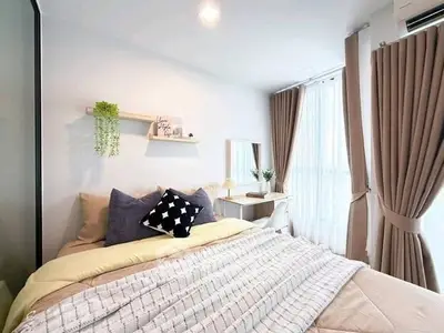 Cozy bedroom with modern decor, large window, and elegant curtains in a bright apartment.