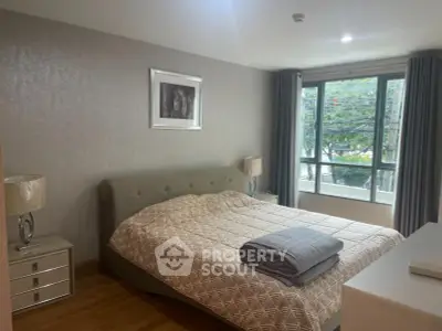 Cozy bedroom with large window and stylish decor in modern apartment.