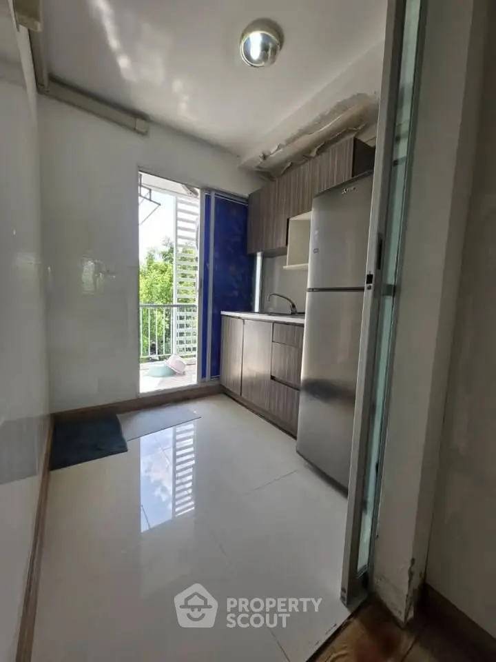 Compact kitchen with modern appliances and balcony access, perfect for urban living.