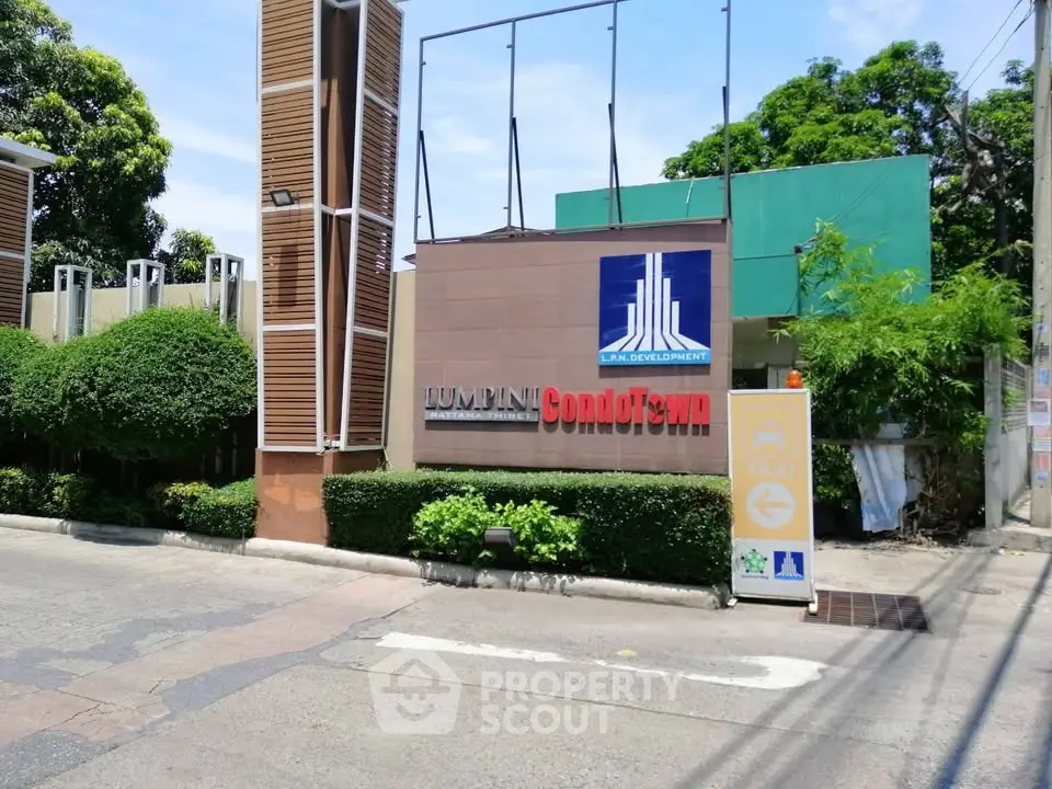 Modern condominium entrance with lush greenery and clear signage