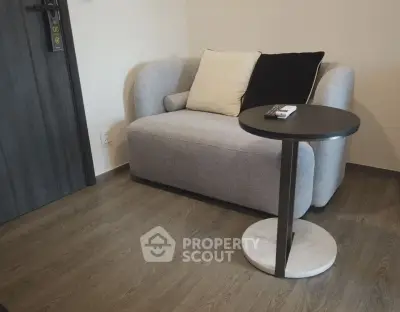 Cozy modern living room with stylish sofa and sleek side table on wooden flooring.