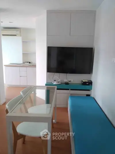 Modern living room with sleek furniture and wall-mounted TV in a cozy apartment.