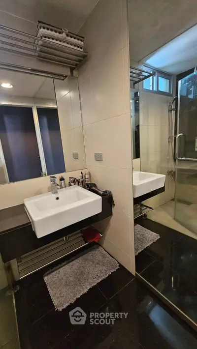 Modern bathroom with sleek design, featuring a large mirror and spacious shower area.