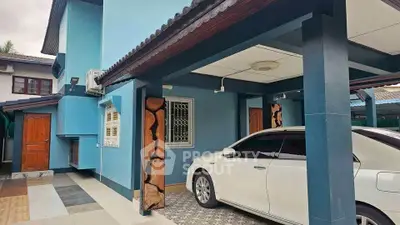 Charming blue house with carport and modern design in a serene neighborhood.