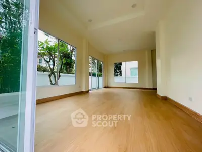 Spacious empty room with large windows and wooden flooring, perfect for customization.