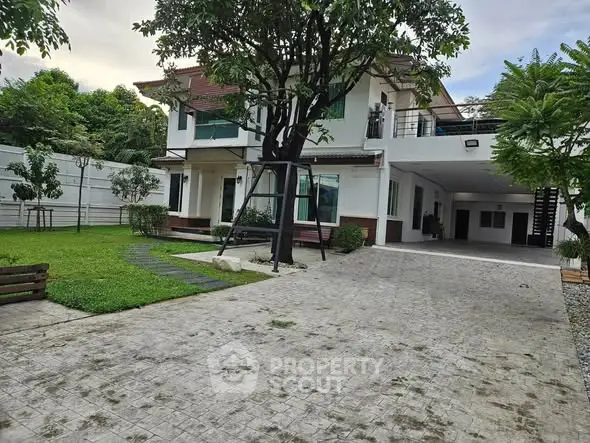 Spacious two-story house with lush garden and driveway in serene neighborhood.