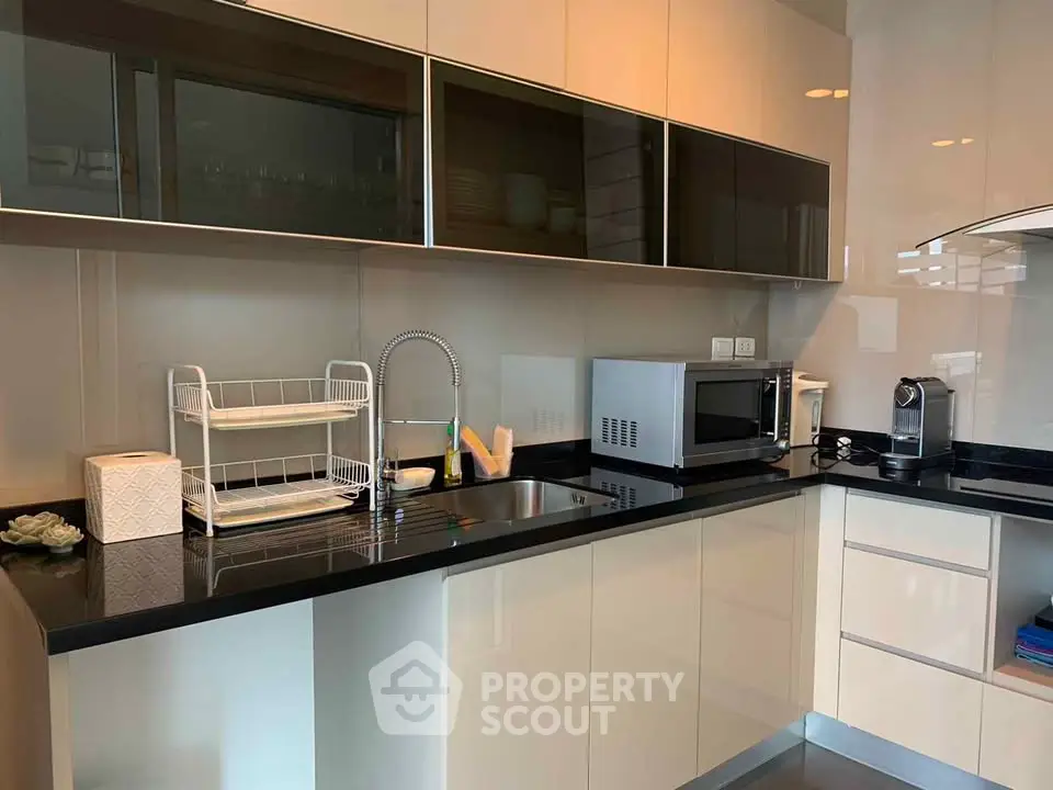 Modern kitchen with sleek cabinetry, microwave, and coffee machine, ideal for contemporary living.