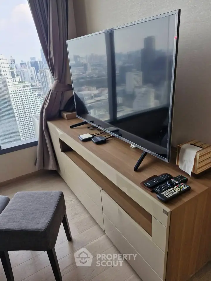 Modern living room with city view, featuring sleek TV setup and stylish furniture.