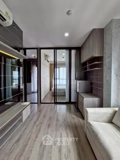 Modern living room with sleek design and glass partition leading to bedroom