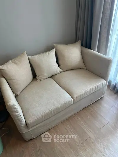 Cozy beige sofa in a modern living room with wooden flooring and natural light.