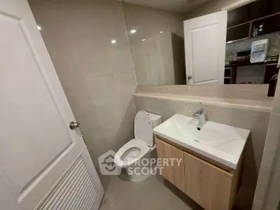 Modern bathroom with sleek fixtures and neutral tones, featuring a compact design for efficient space use.