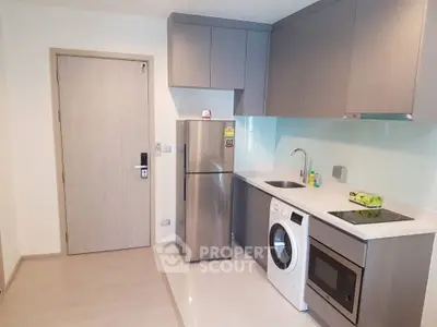 Modern kitchen with sleek appliances and compact design, featuring a washing machine and stainless steel fridge.