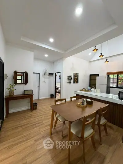 Spacious kitchen with open layout and modern dining area, featuring elegant wooden flooring and stylish lighting.
