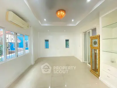 Spacious living room with elegant chandelier and large windows for natural light.