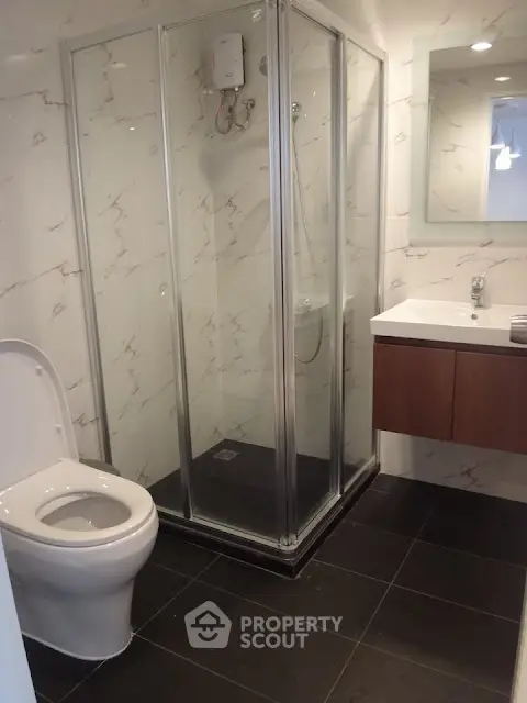 Modern bathroom with glass shower enclosure and sleek vanity in a contemporary apartment.
