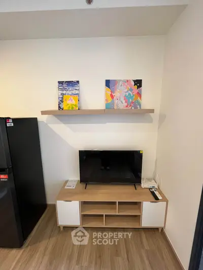 Modern living room with stylish TV stand and artwork, featuring sleek wooden flooring and contemporary decor.