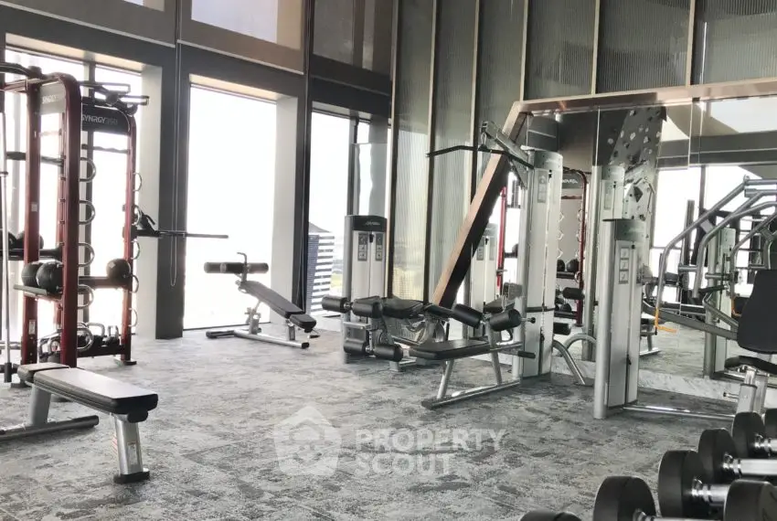 Spacious modern gym with state-of-the-art equipment and large windows offering natural light.