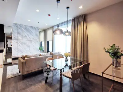 Modern living room with elegant glass dining table and cozy sofa in a stylish apartment.
