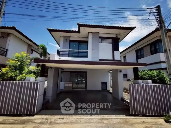 Modern two-story house with gated driveway and contemporary design.