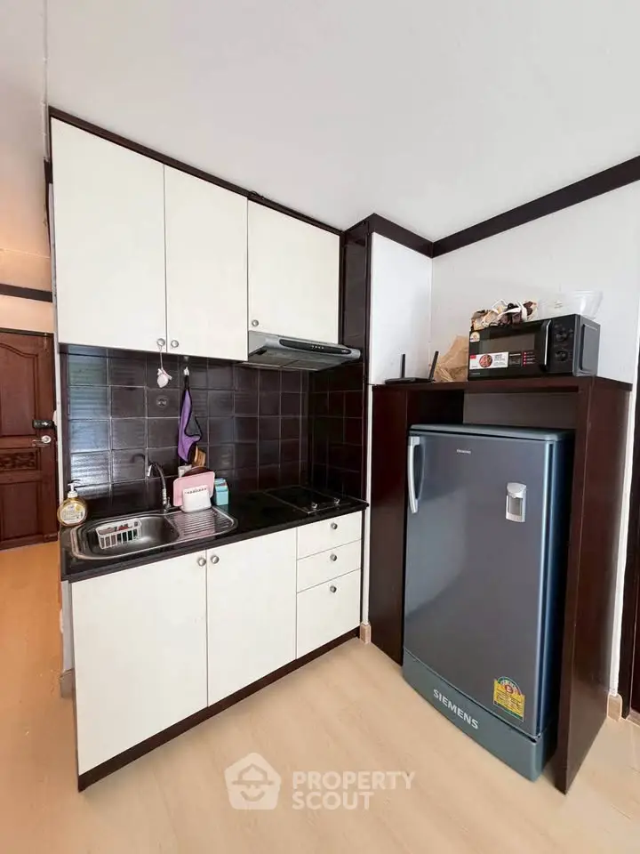 Compact kitchen with modern appliances and sleek cabinetry in a cozy apartment.