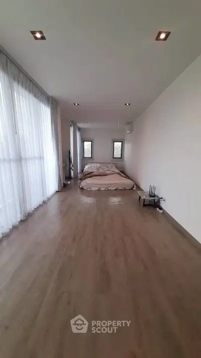 Spacious minimalist bedroom with large windows and wooden flooring