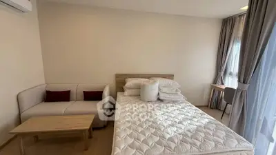 Cozy bedroom with natural light, featuring a comfortable bed, sofa, and study area.