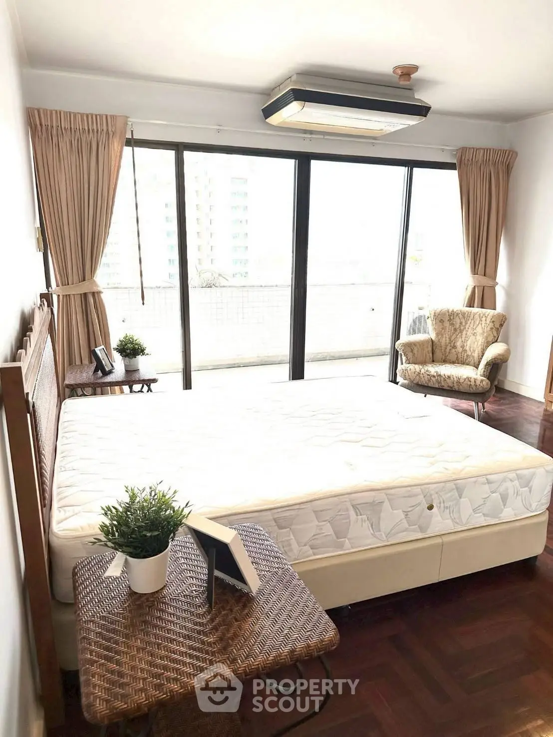 Spacious bedroom with large windows and balcony access, featuring elegant furniture and natural light.