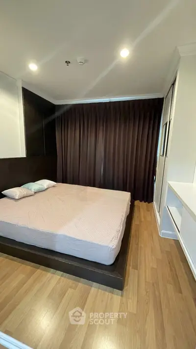 Modern bedroom with wooden flooring and cozy lighting in a stylish apartment.