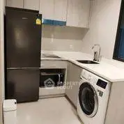 Modern kitchen with sleek appliances including fridge, oven, and washing machine in compact layout.