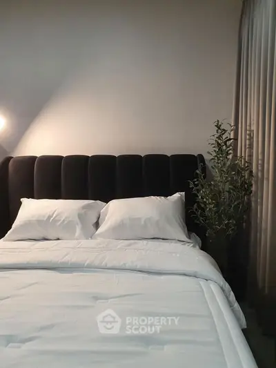 Elegant bedroom with plush headboard and soft lighting, perfect for relaxation.