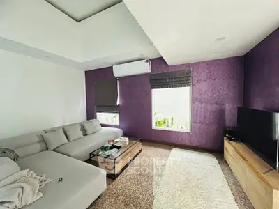Modern living room with stylish purple accent wall and cozy sectional sofa