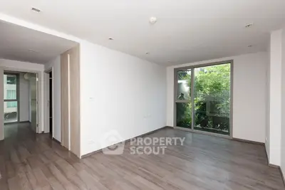 Spacious empty living room with large window and wooden flooring