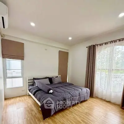 Spacious bedroom with modern decor and large window offering natural light.