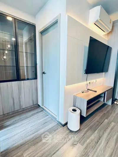 Modern living room with sleek TV setup and air conditioning, featuring stylish wood flooring and contemporary design.