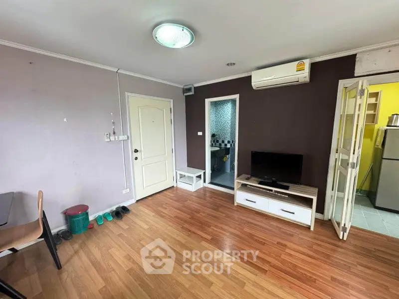 Cozy living room with wooden flooring, TV unit, and air conditioning in modern apartment.