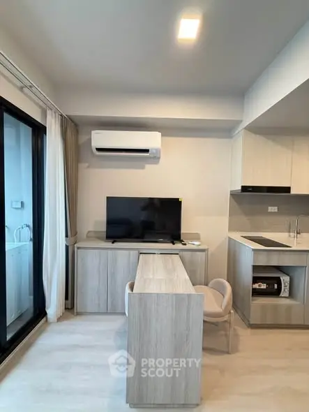 Modern living room with sleek furniture and built-in kitchen appliances in a contemporary apartment.