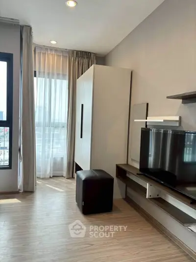 Modern living room with sleek furniture and large window offering natural light.