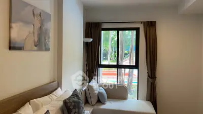 Cozy living room with large window overlooking garden and pool, featuring stylish decor and comfortable seating.
