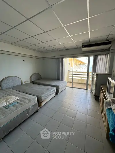 Spacious bedroom with twin beds and balcony access in a modern apartment.