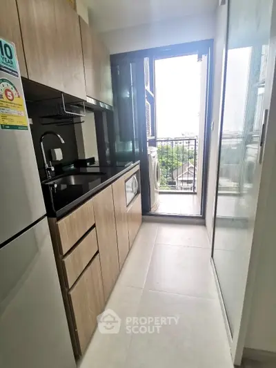 Modern kitchen with sleek cabinetry and balcony access in urban apartment